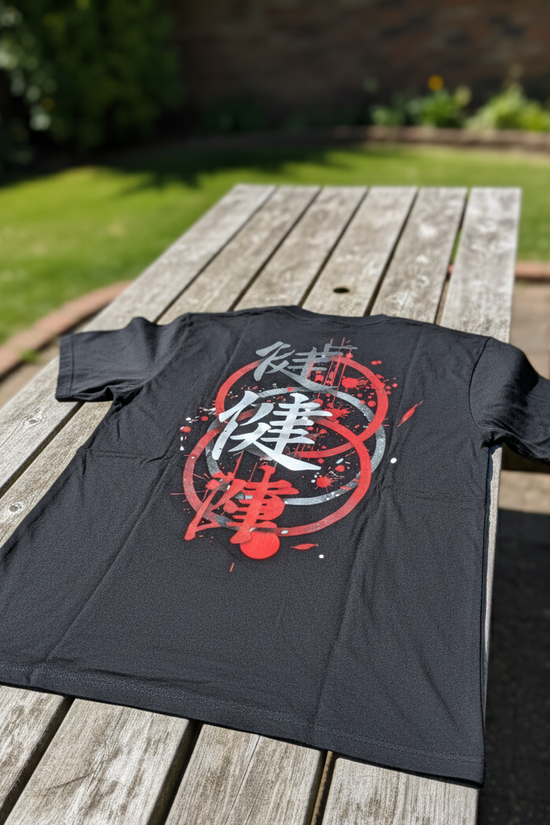 Black t-shirt with red and white graphic design on a wooden table outdoors